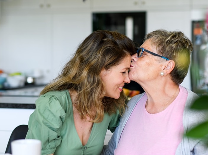 Adult daughter getting kissed on the forehead by her mother